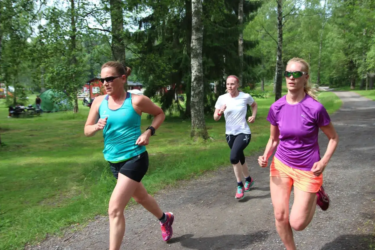 Tre kvinnor springer i skogen, kanske under ett tr&auml;ningspass med korta intervaller.
