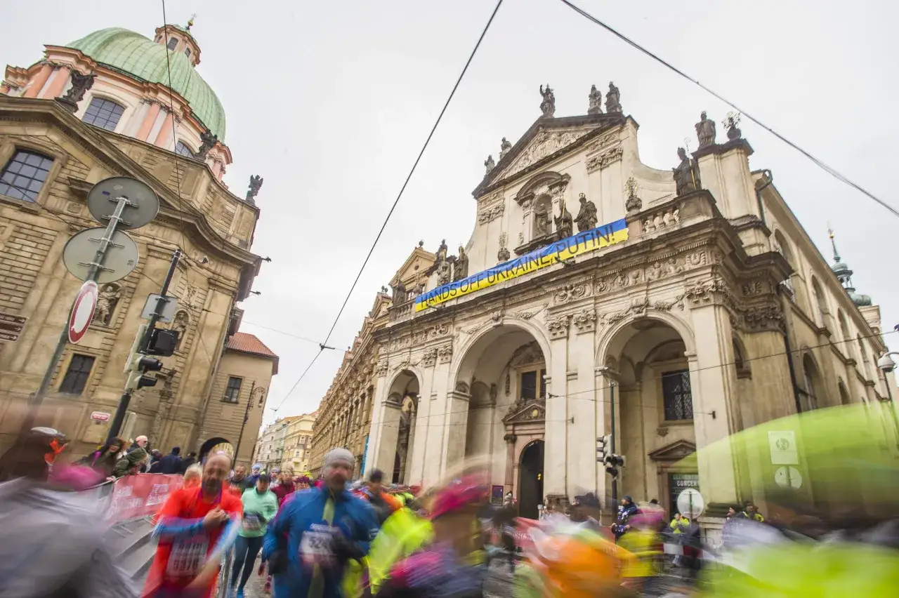 L&ouml;pare i Prag halvmarathon passerar en byggnad med en banderoll 