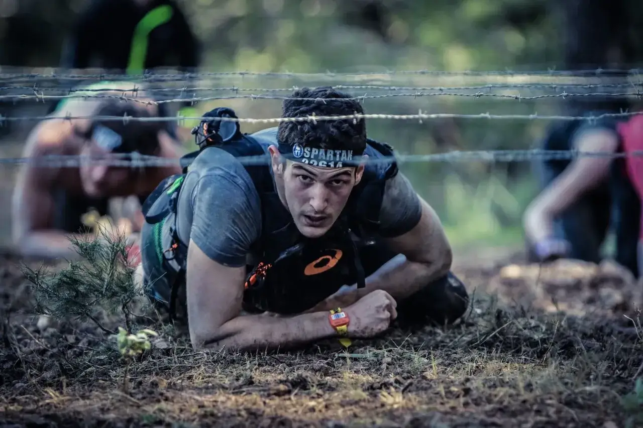 Man kryper under taggtr&aring;d i ett ocr sport-lopp.
