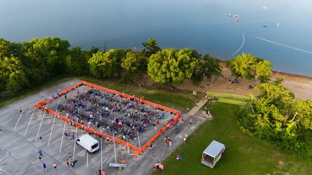 Förberedelser inför en triathlon vid en sjö. Många cyklar står uppradade i ett avspärrat område, redo för tävlingen. En scen som påminner om Runners World Triathlon.