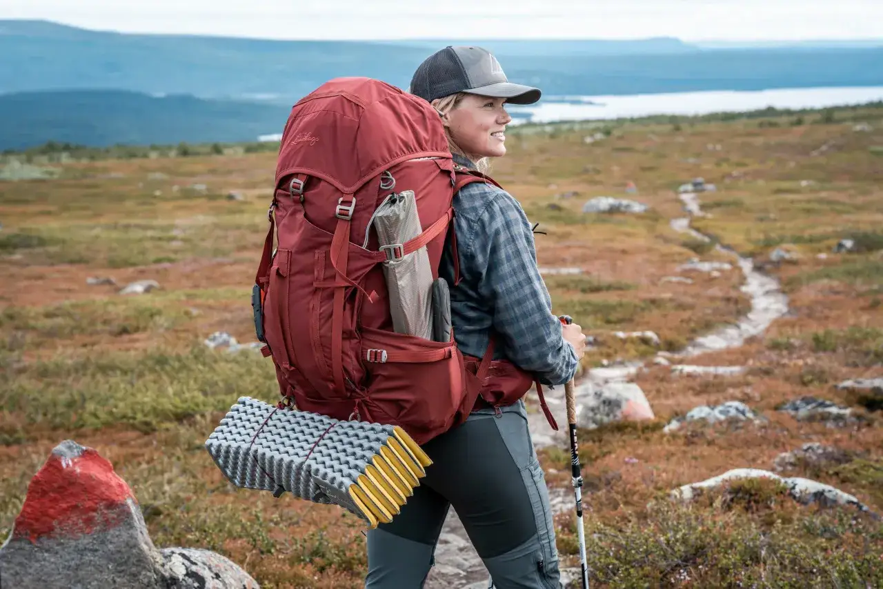 Vandrare med stor ryggs&auml;ck och liggunderlag, redo f&ouml;r &auml;ventyr. All bamm utrustning &auml;r med f&ouml;r en bekv&auml;m tur i fj&auml;llen.