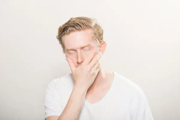 Man med slutna ögon och hand över munnen, som om han drabbats av en plötslig kramp i tårna brist.